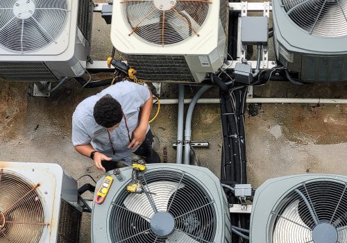 Young HVAC technician using modern technology to work on and maintain outdoor HVAC units at condo.